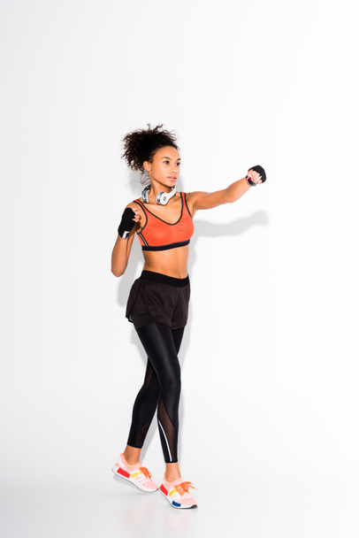 mooie atletische Afro-Amerikaanse Sportvrouw opleiding in sport handschoenen op wit - Foto, afbeelding