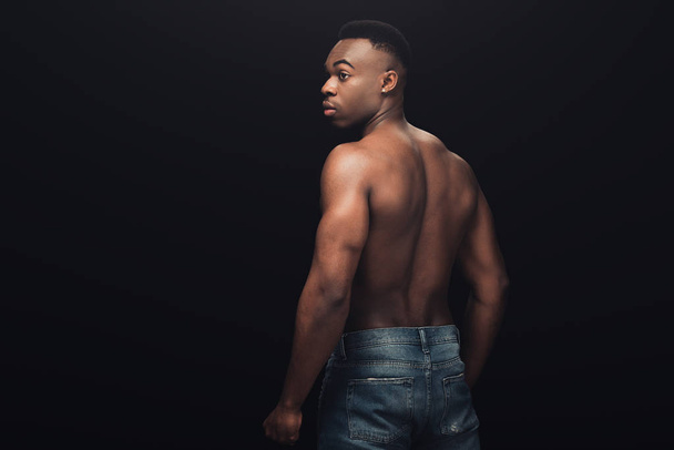 back view of sexy muscular african american man in denim posing isolated on black with copy space - Foto, afbeelding