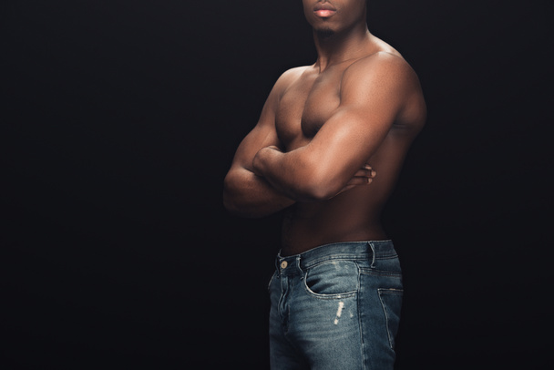 cropped view of sexy muscular african american man in denim posing with crossed arms isolated on black - Photo, Image