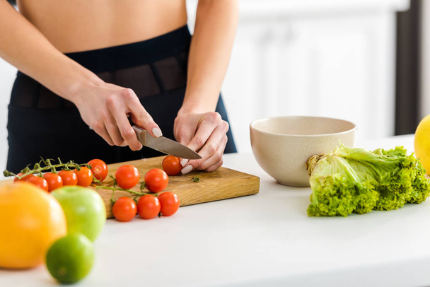 cropped view of woman cutting red cherry tomatoes on cutting board  - Photo, Image