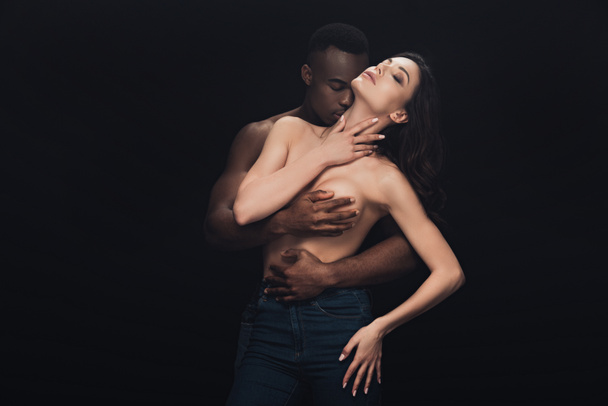 beautiful half-naked interracial couple passionately embracing isolated on black with copy space - Foto, Imagem