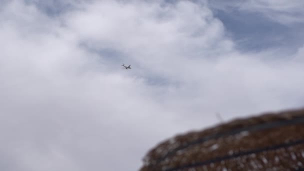 Vliegtuig vliegt op de achtergrond en op de voorgrond-strand paraplu onscherp. - Video