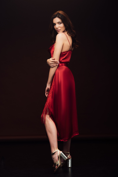 Kırmızı elbise poz ve siyah üzerinde izole kamera bakarak güzel şehvetli kadın - Fotoğraf, Görsel