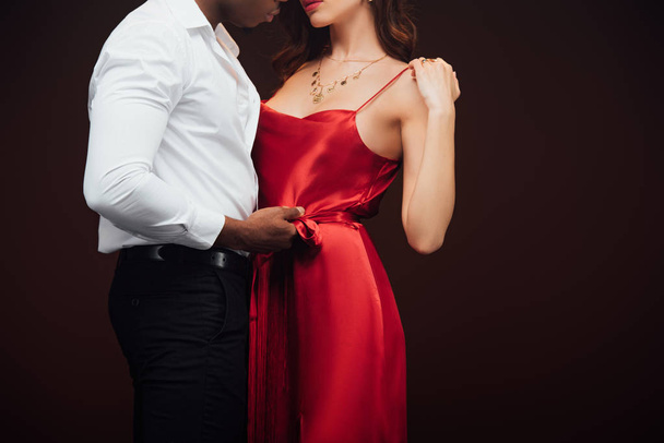 cropped view of african american man embracing woman in red dress isolated on black with copy space - Valokuva, kuva