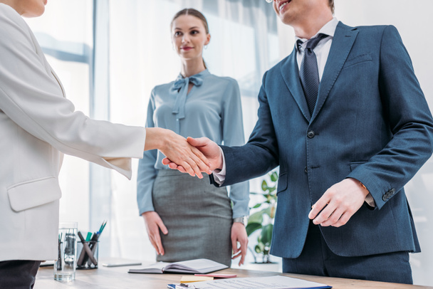 cropped view of cheerful recruiter shaking hands with woman near attractive colleague in office - Photo, Image