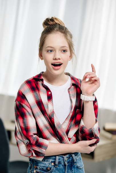Erstauntes Teenager-Kind im rot karierten Hemd, das mit offenem Mund wegschaut - Foto, Bild