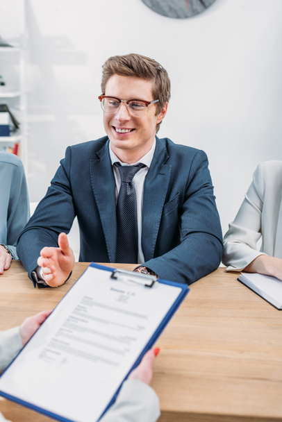 selective focus of cheerful recruiter near colleagues and woman holding clipboard on job interview  - Photo, Image