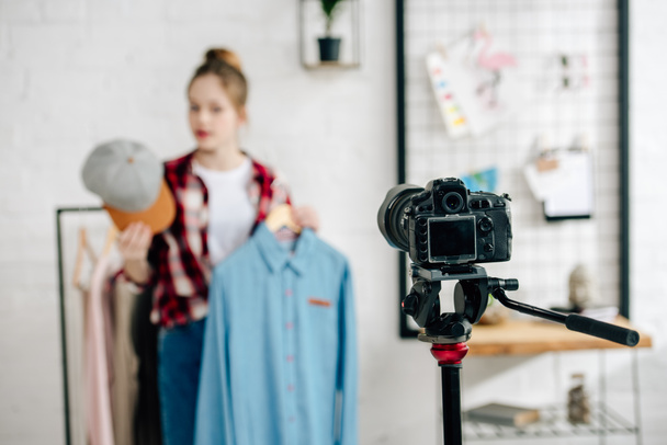 Selective focus of teenager holding cap and shirt in front of video camera - Fotoğraf, Görsel