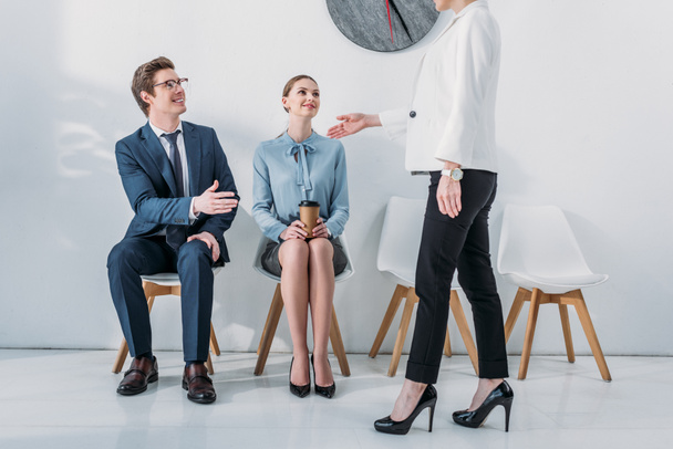 cropped view of recruiter standing and gesturing near attractive woman and cheerful man in glasses  - 写真・画像