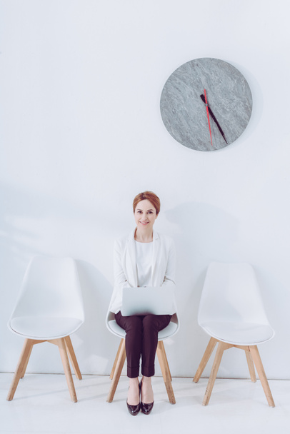 cheerful employee sitting on chair with laptop while waiting job interview  - Fotoğraf, Görsel