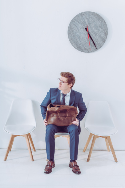 worried man in glasses holding briefcase while waiting job interview  - Foto, imagen
