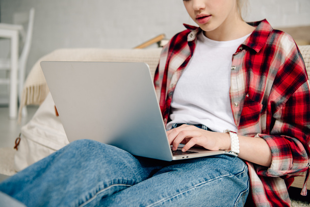 Cropped view of teenage kid in checkered shirt using laptop  - Foto, Imagen