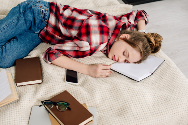 Genç içinde damalı gömlek Sleeping üzerinde yatak ile kitap ve Smartphone - Fotoğraf, Görsel