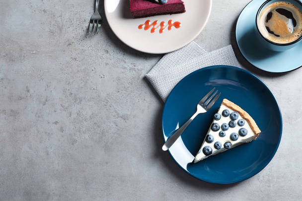 Flat lay composition with piece of tasty blueberry cake and space for text on gray table - Foto, Imagen