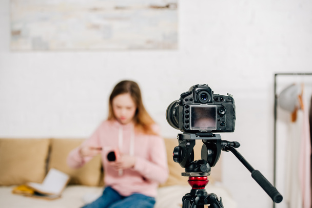 Selective focus of teenage blogger sitting in front of video camera - Foto, Imagem