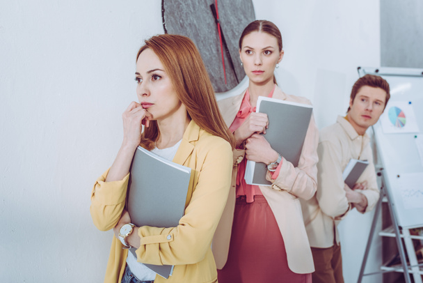 selective focus of worried attractive women and man waiting in line with folders   - Fotoğraf, Görsel