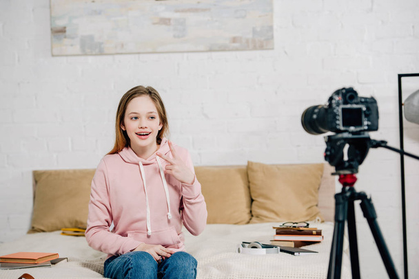 Joyeuse blogueuse adolescente montrant signe de paix à la caméra vidéo
 - Photo, image