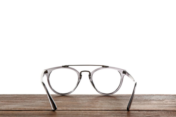 Glasses on wooden table against white background. Ophthalmologist consultation - Фото, изображение