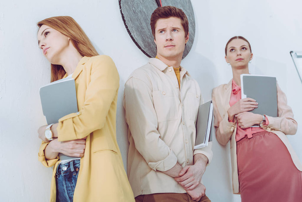 low angle view of women and handsome man waiting in line with folders  - 写真・画像