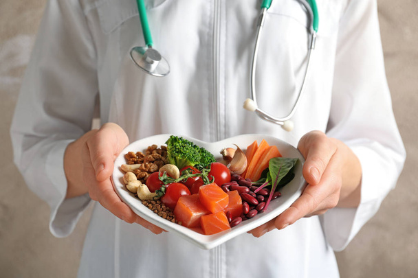 Doctor holding plate with products for heart-healthy diet, closeup - Foto, Bild
