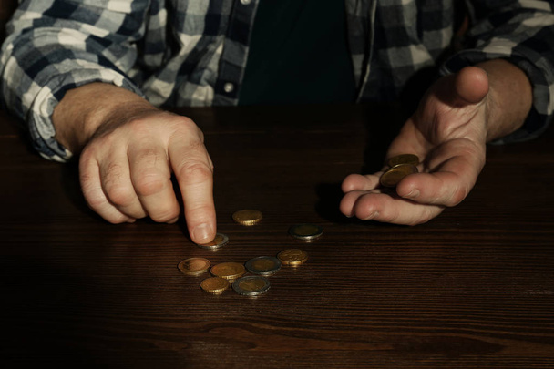 Poor senior man counting coins at table, closeup - Fotó, kép