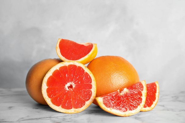 Fresh tasty grapefruits on table against light background - Foto, imagen