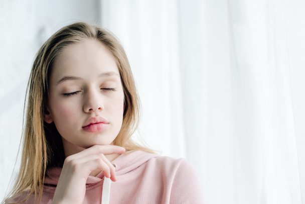 Laza tizenéves gyerek rózsaszín kapucnis zárt szemmel - Fotó, kép