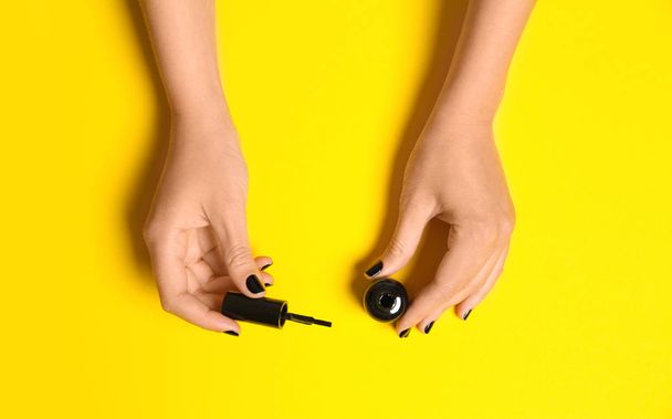 Woman applying nail polish on color background, top view - Foto, imagen