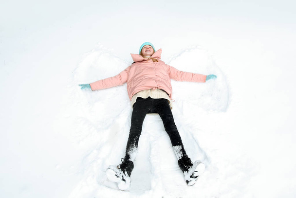 Teenage girl making snow angel on winter day - Photo, Image