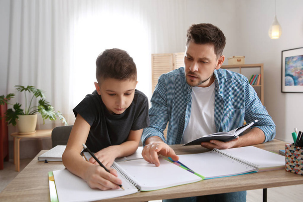 Dad helping his son with homework in room - Foto, afbeelding