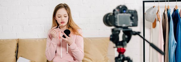 Panoramic shot of teenager kid applying lip gloss in front of video camera - Foto, afbeelding