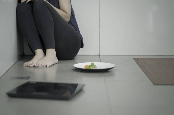 Lonely woman with salad and weight scales - Foto, afbeelding