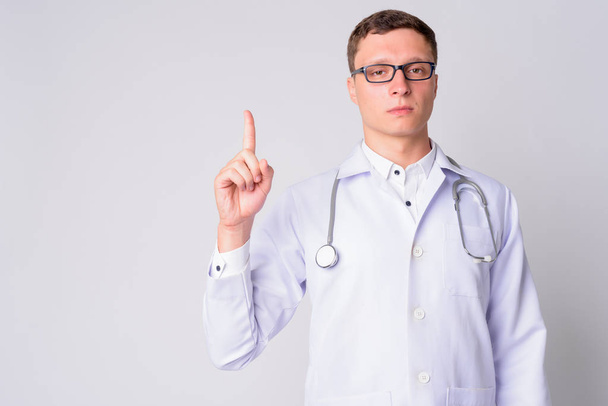 Portrait of young man doctor pointing up - Foto, immagini