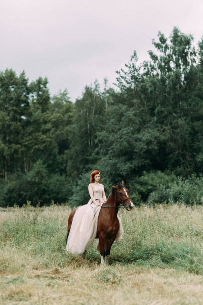 The bride on a horse in the field. Beautiful wedding and photo shoot with a horse. - Fotoğraf, Görsel