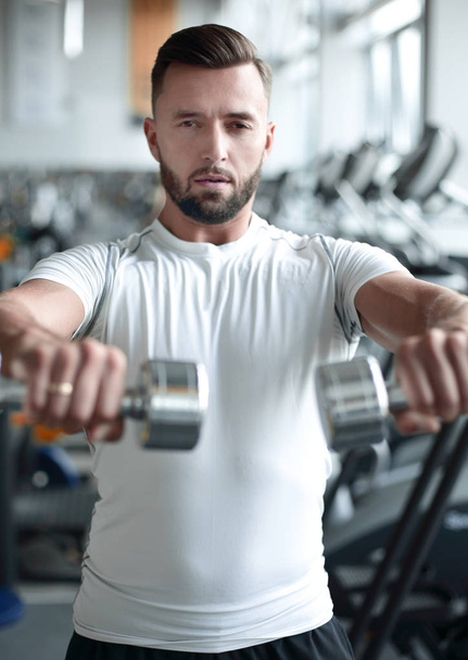 close up.stylish young man working with dumbbells in the gym. - 写真・画像