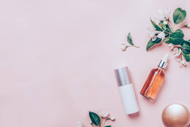 Pink natural cosmetics: oil, serum, cream, mask on background with flowers. Flat lay, minimalism. - Photo, Image