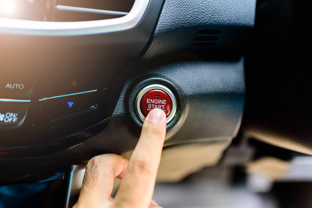 Палец азиата нажимает кнопку, чтобы завести или остановить двигатель автомобиля
 - Фото, изображение