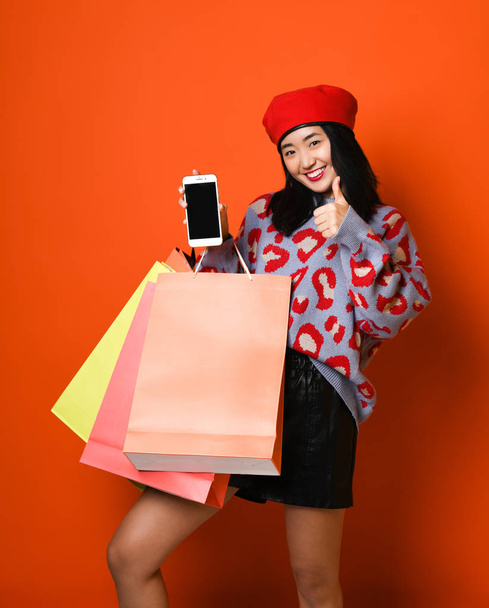 Young asian woman with shopping bags on color background - Foto, Imagem