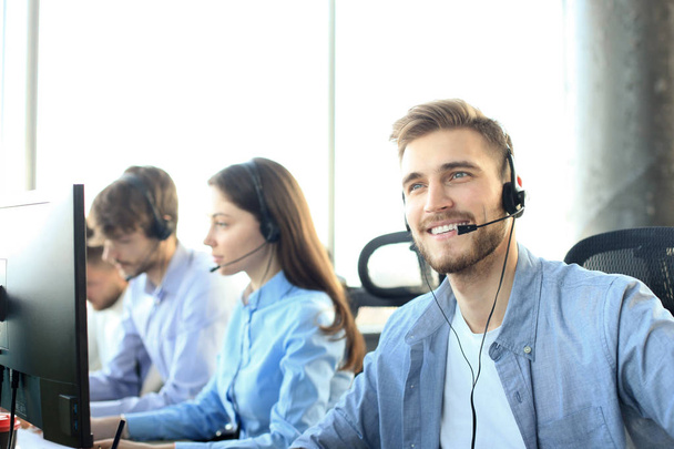 Portrait of call center worker accompanied by his team. Smiling customer support operator at work. - Foto, Imagem