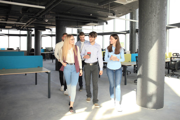Full length of young people in smart casual wear discussing business and smiling while walking through the office. - Foto, imagen