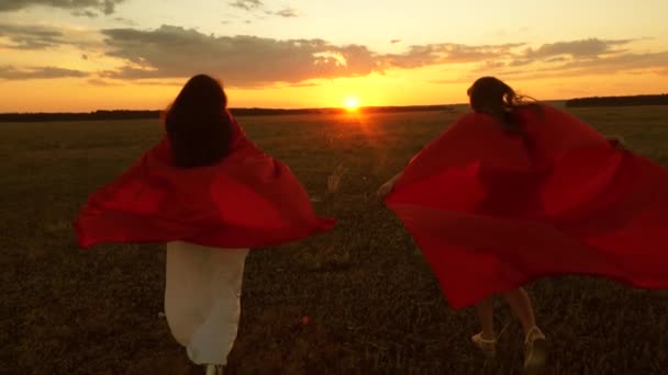 Girls play superheroes running across field with wheat against blue sky - Footage, Video