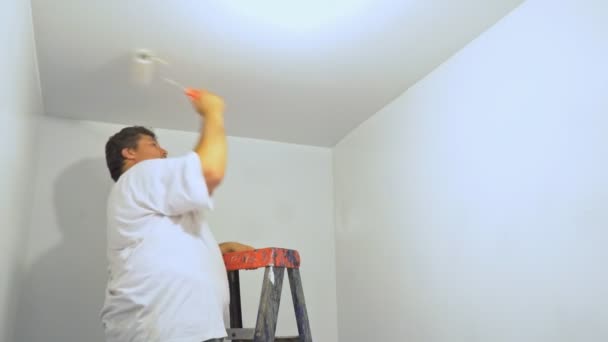 Pintor hombre en el trabajo con la pintura de rodillos escalera de techo en primer plano
 - Metraje, vídeo