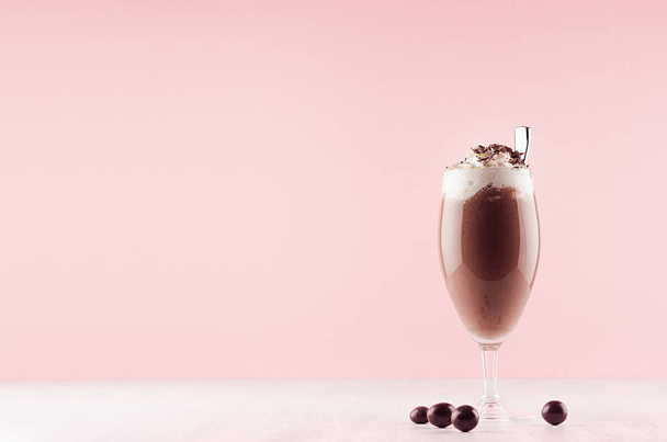 Chocolate fresh shake in graceful glass with candies, whipped cream, chocolate chips and straw on pink background. - Fotoğraf, Görsel
