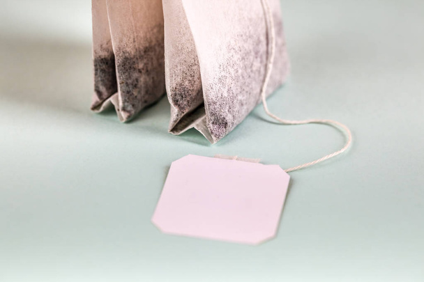 Two tea bags with white label isolated on light background - Foto, immagini