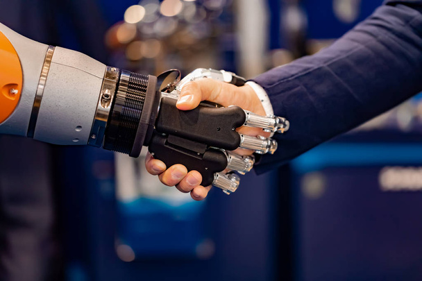 Hand of a businessman shaking hands with a Android robot. - Foto, imagen