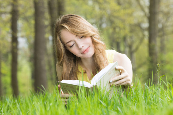 Girl reading book on grass - Foto, afbeelding