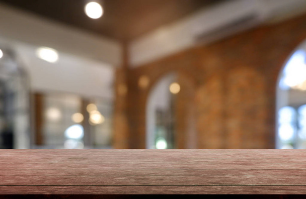 Mesa de madera vacía frente al fondo borroso abstracto del interior del restaurante, cafetería y cafetería. se puede utilizar para mostrar o montar sus productos - Imagen
 - Foto, Imagen