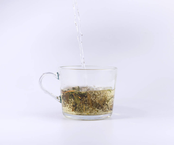 наливаючи гарячу воду в скляну чашку з чаєм, ізольовані на білому фоні
 - Фото, зображення
