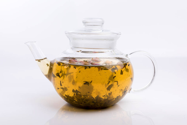 Glass teapot with herbal tea and roses isolated on white background - Foto, afbeelding