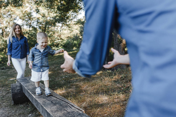 Malý chlapec dělá svůj první krok od matky k otci v parku - Fotografie, Obrázek